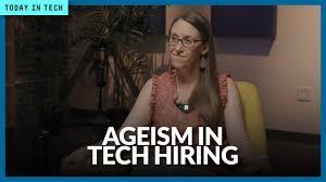 That's a screenshot from a video segment, likely from a news program or interview.  It shows a middle-aged woman with glasses, seated in a chair.  The overlay text "AGEISM IN TECH HIRING" strongly suggests the video's topic is age discrimination in the technology industry, with the woman possibly being interviewed about her experiences or expertise on the subject. The setting appears to be a professional studio or interview room.